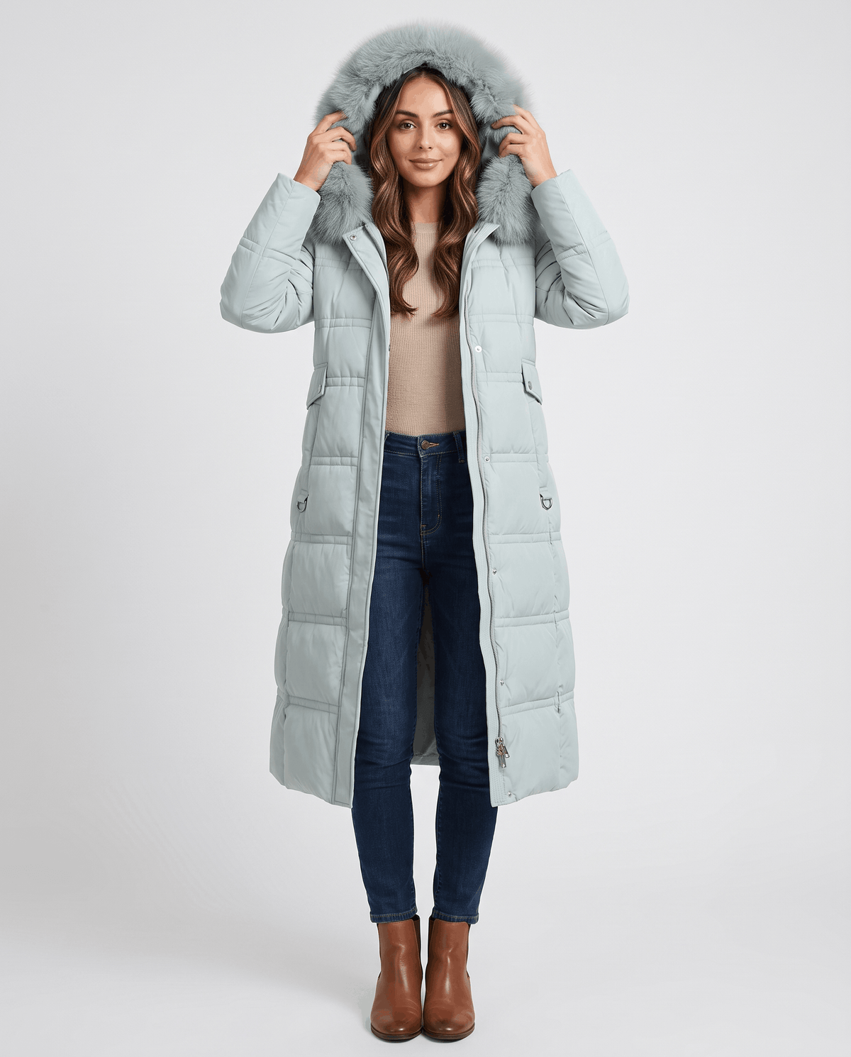 A woman wearing a light blue longline quilted winter parka with a plush fur-trimmed hood, front view