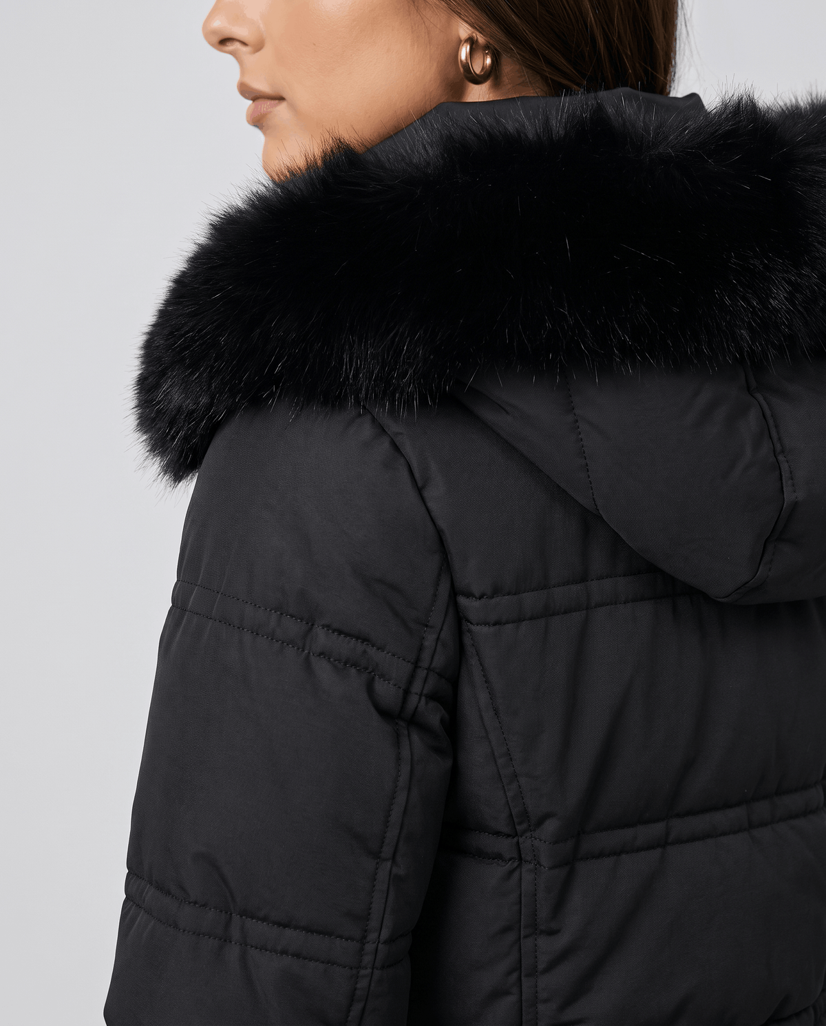 Close-up of a black quilted winter parka showing the plush fur-trimmed hood