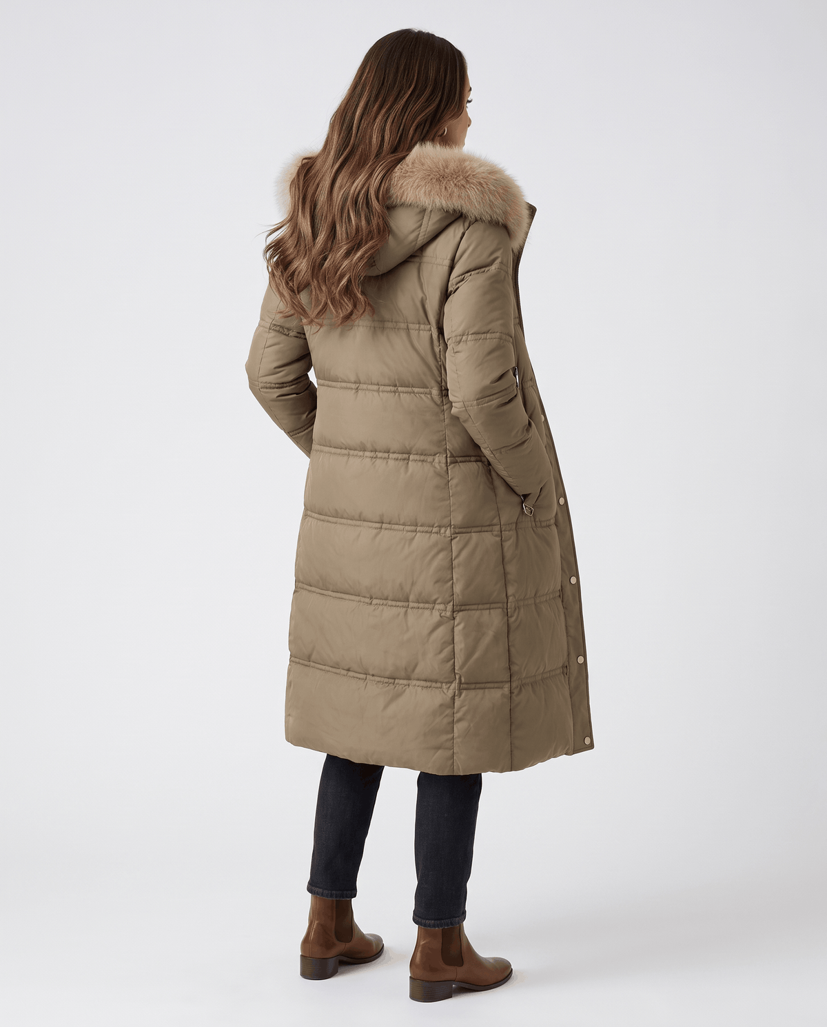 A woman wearing an olive green longline quilted winter parka with a plush fur-trimmed hood, shown from the back