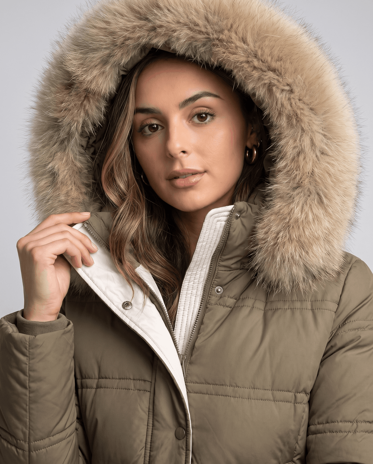 Close-up of a woman wearing an olive green quilted winter parka, showing the plush fur-trimmed hood