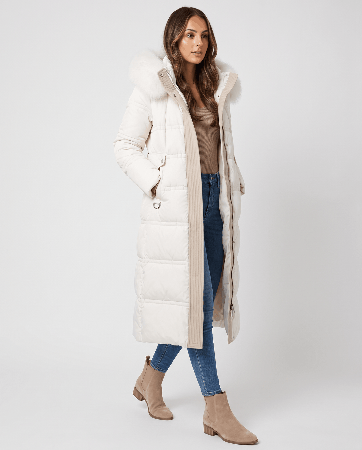 A woman wearing a white longline quilted winter parka with a plush fur-trimmed hood