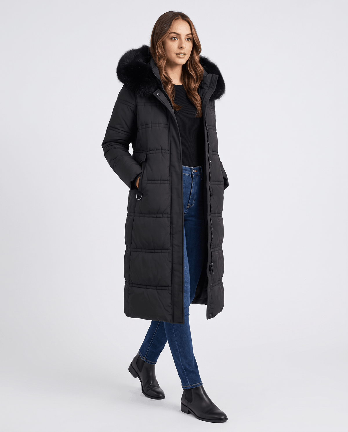 A woman wearing a black quilted winter parka with a longline puffer design and plush fur-trimmed hood