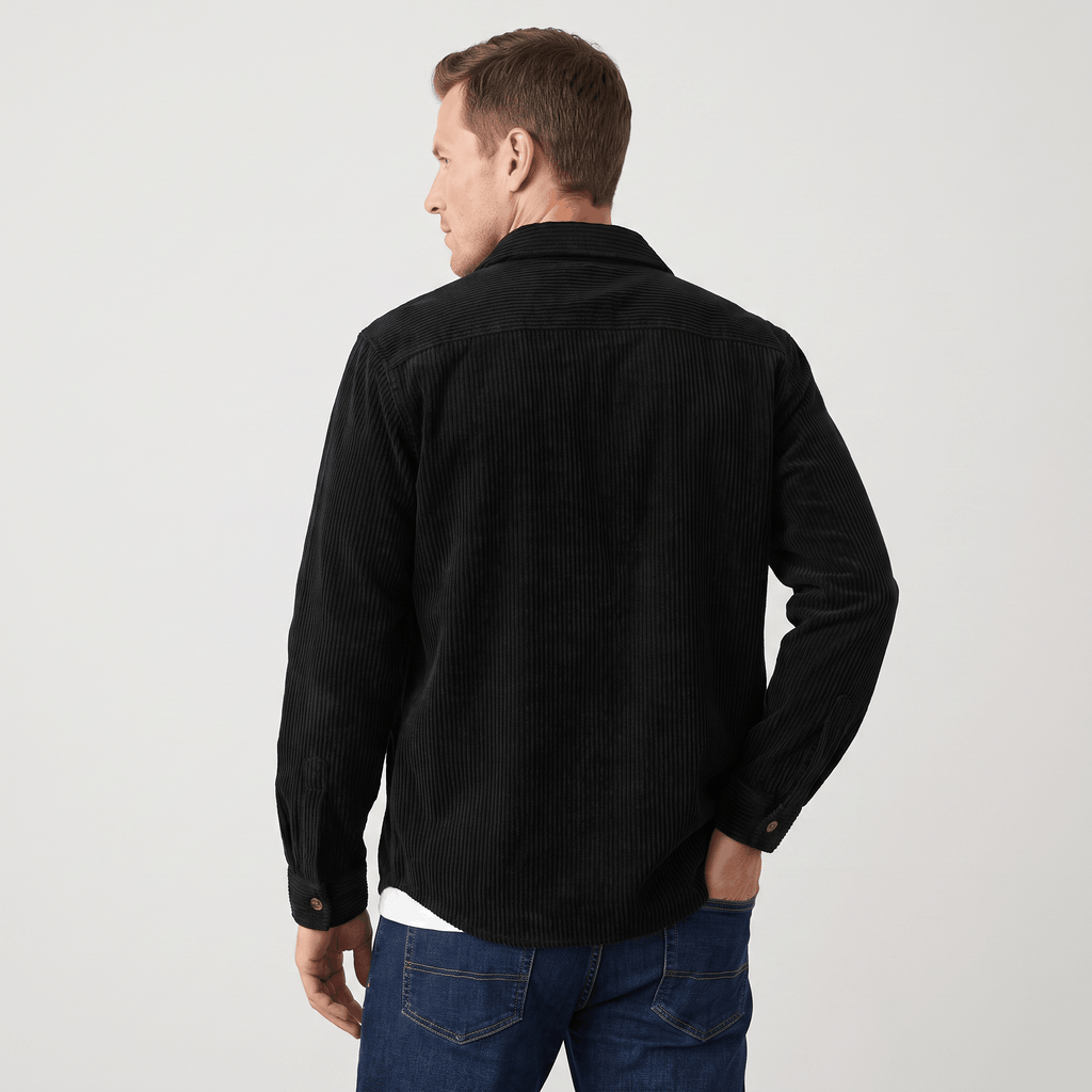 Black wide wale corduroy overshirt in a relaxed fit with a structured collar, worn over a white tee and blue jeans.