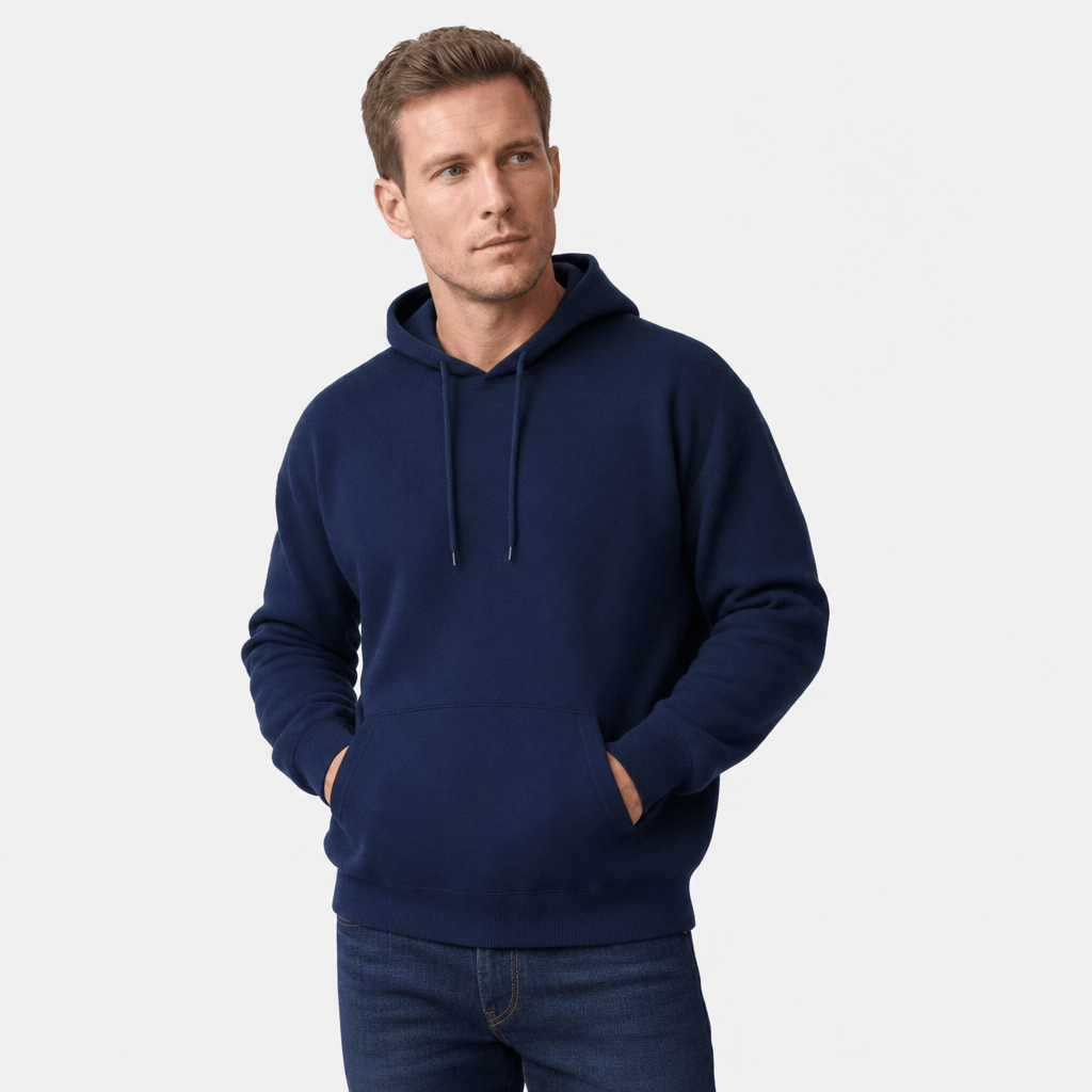 Male model wearing a navy blue pullover hoodie with hands in the kangaroo pocket.