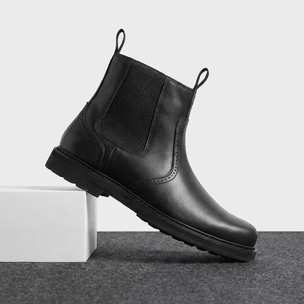 Pair of black Chelsea boots displayed together, showing the elastic panels, pull tabs, and smooth finish.