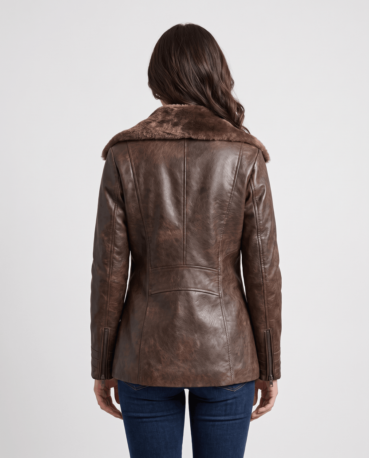 A woman wearing a dark brown shearling leather jacket with an oversized collar and full-zip front, shown from the back