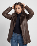 A woman wearing a dark brown shearling leather jacket with an oversized collar and full-zip front