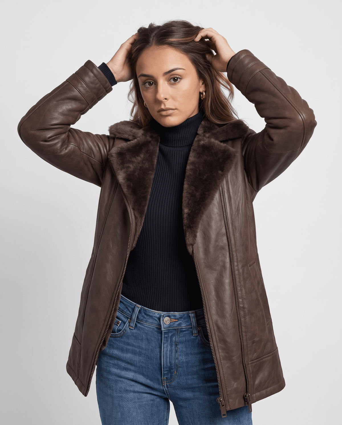 A woman wearing a dark brown shearling leather jacket with an oversized collar and full-zip front