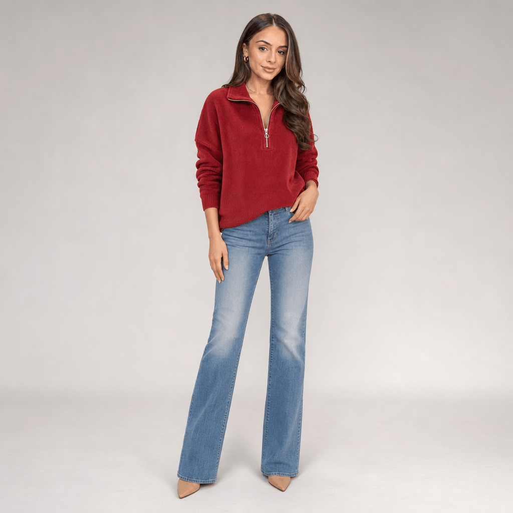 Full-body view of the woman wearing the burgundy red ribbed half-zip sweater with blue jeans.
