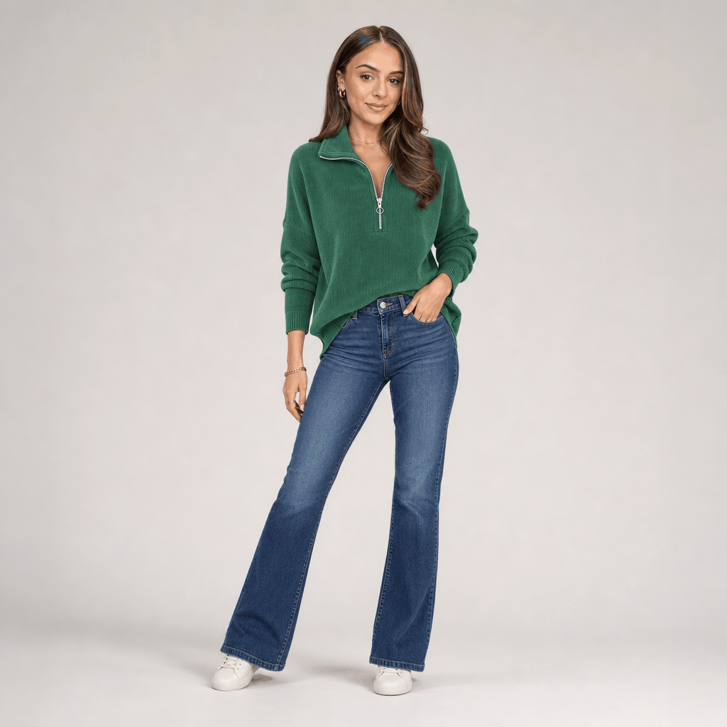 Full-body view of the woman wearing the forest green ribbed half-zip sweater with blue jeans.