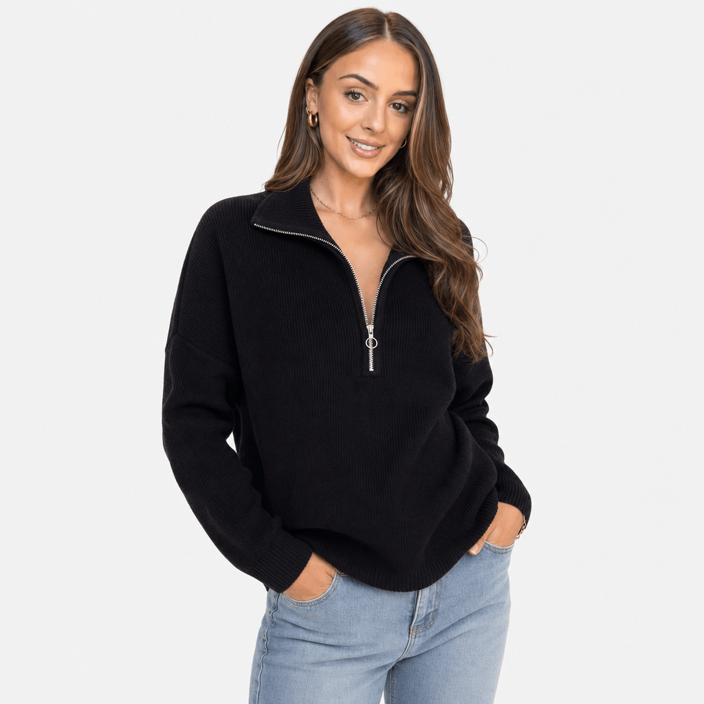 Woman wearing a black ribbed half-zip sweater with blue jeans, shown in a relaxed standing pose.