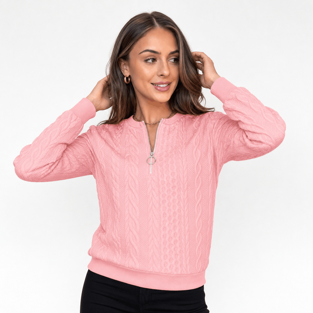 Woman wearing a soft pink ribbed half-zip sweater, shown adjusting her hair.