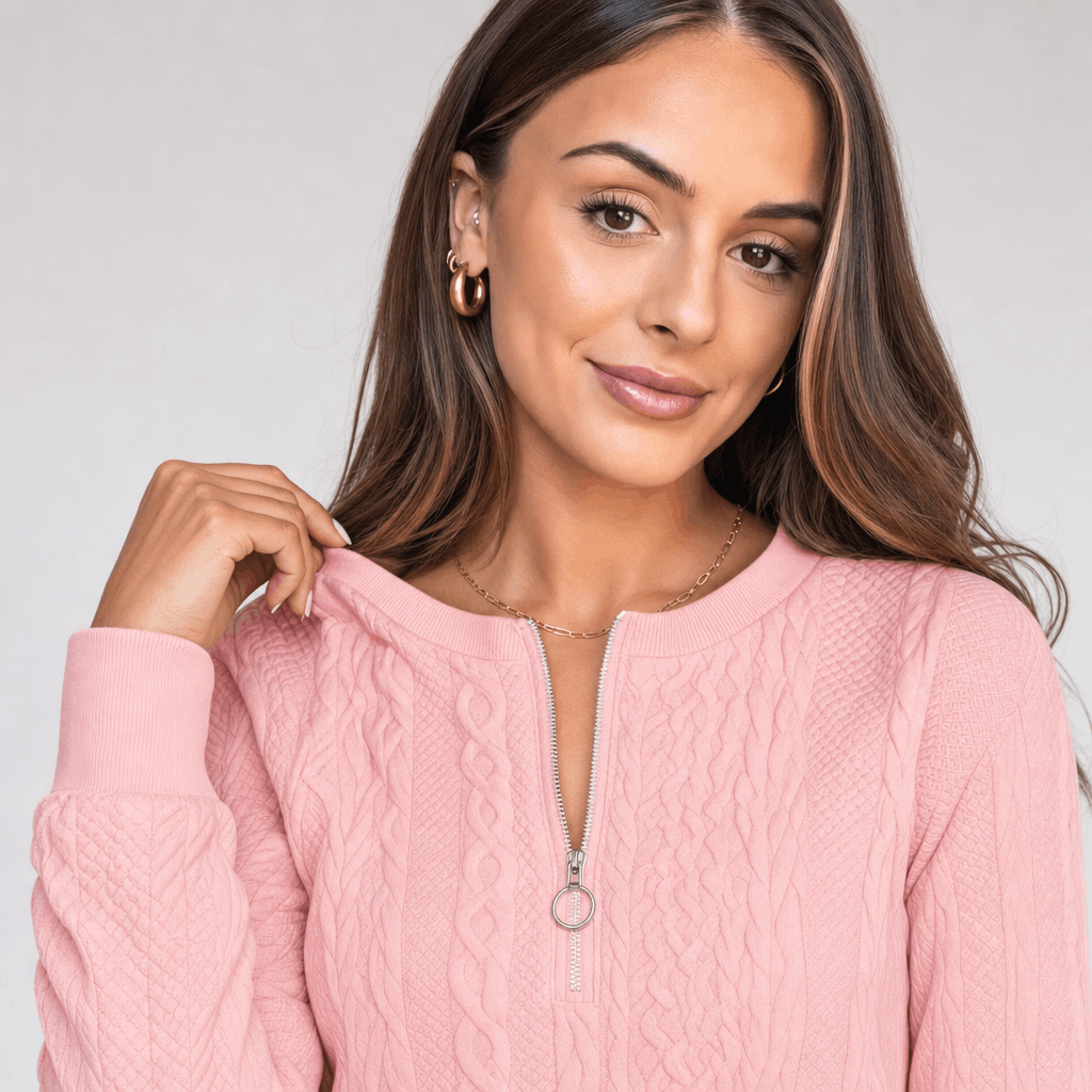 Close-up portrait of the woman wearing the soft pink ribbed half-zip sweater.