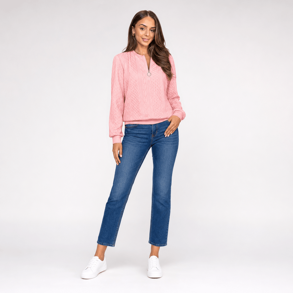 Full-body view of the woman wearing the soft pink ribbed half-zip sweater with blue jeans.