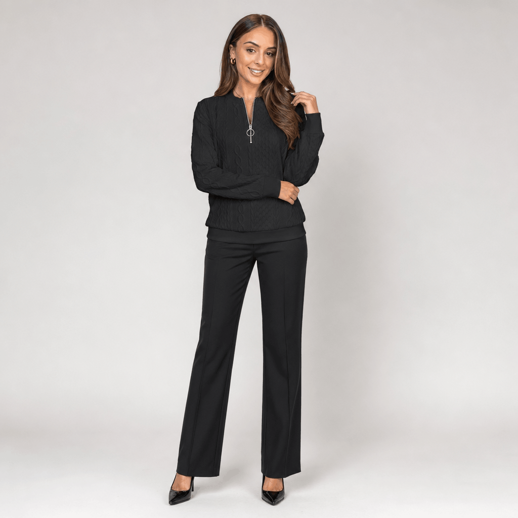 Full-body view of the woman wearing the black sweater with black pants.