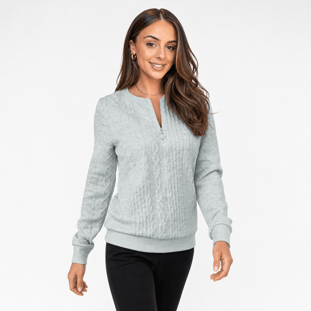 Woman wearing a light gray ribbed half-zip sweater in a standing pose.