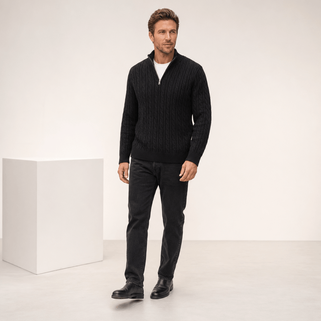 Black cable knit quarter-zip sweater with a funnel collar, ribbed cuffs, and hem, worn over a white shirt.
