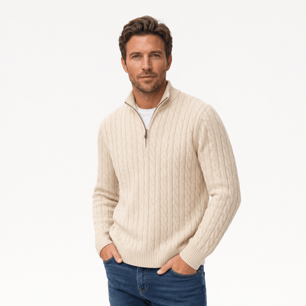 Cream cable knit quarter-zip sweater with a funnel collar, ribbed cuffs, and hem, worn over a white shirt with blue jeans.