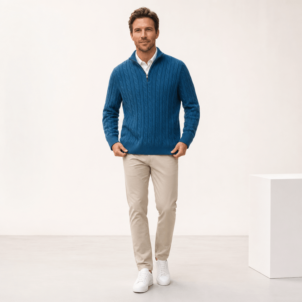 Blue cable knit quarter-zip sweater with a funnel collar, ribbed trim, and long sleeves, worn over a white shirt.