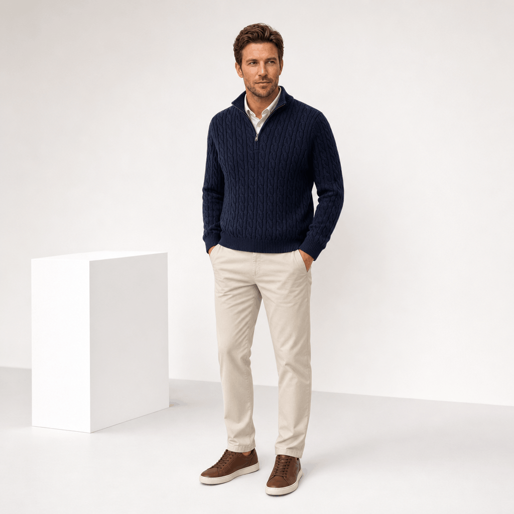 Navy cable knit quarter zip sweater with funnel collar, ribbed trim, and long sleeves worn over a collared shirt.