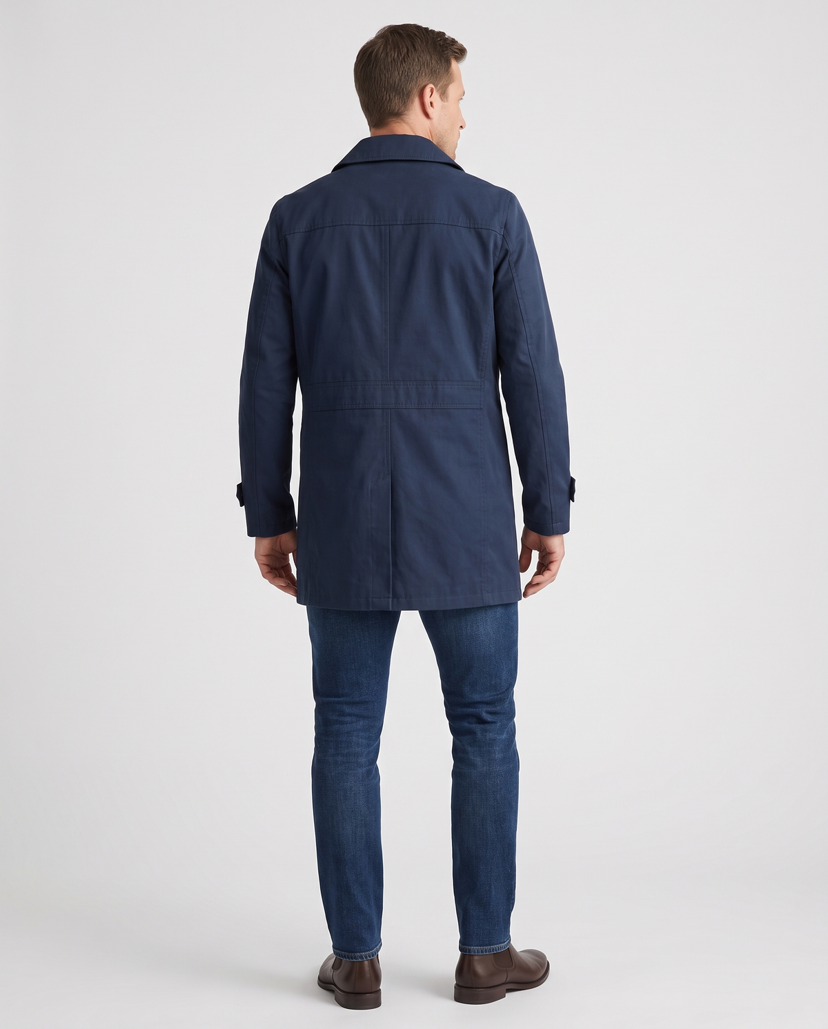 A man wearing a navy blue single-breasted trench coat with structured lapels and a tailored fit, back view