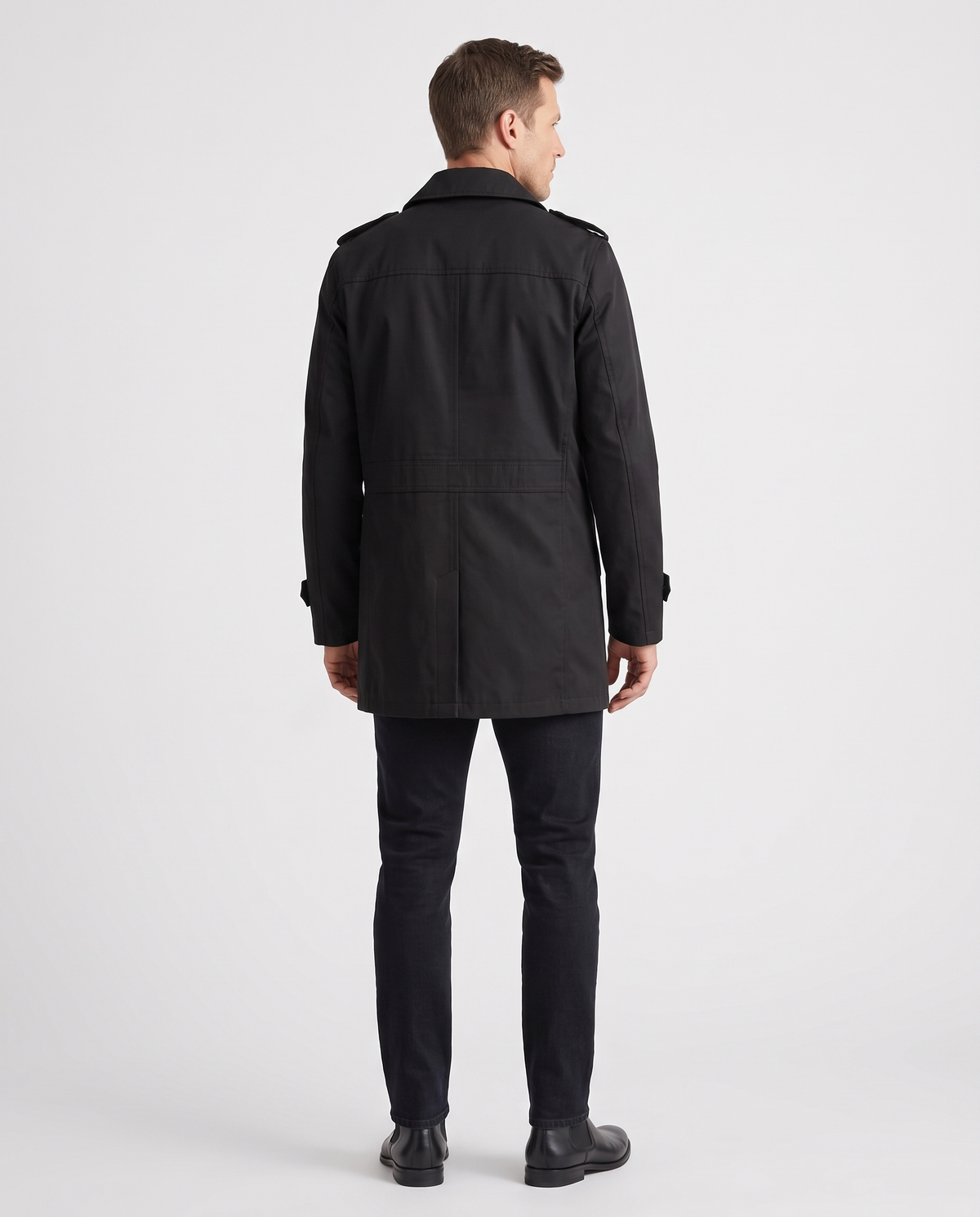A man wearing a black single-breasted trench coat with structured lapels and a tailored fit, back view