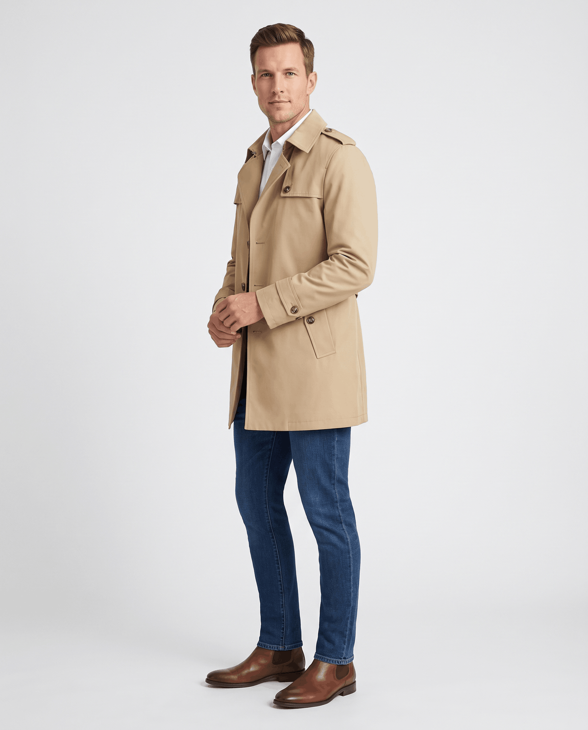 A man wearing a beige single-breasted trench coat with structured lapels and a tailored fit, side view