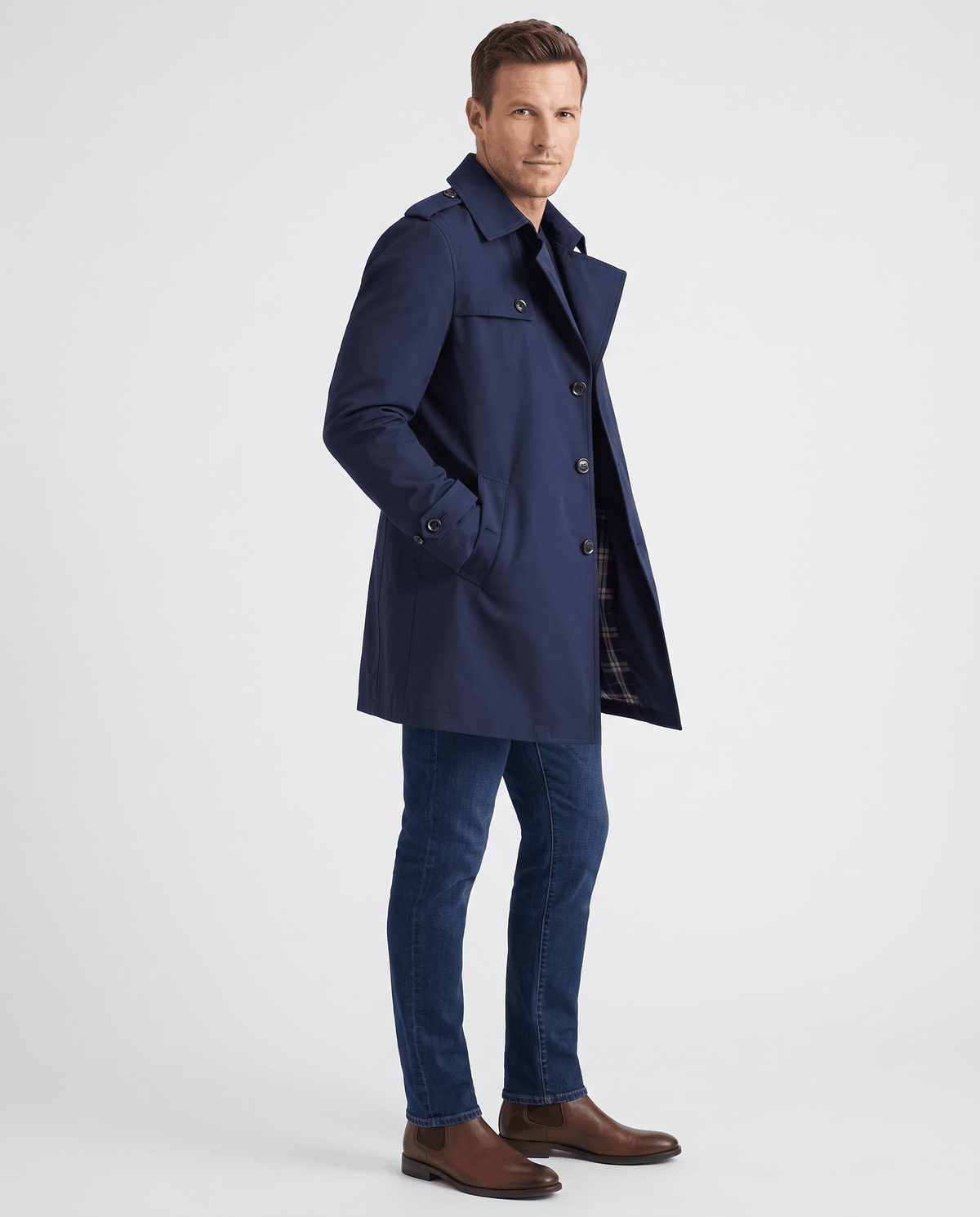 A man wearing a navy blue single-breasted trench coat with a mid-length fit, structured lapels, and tailored silhouette