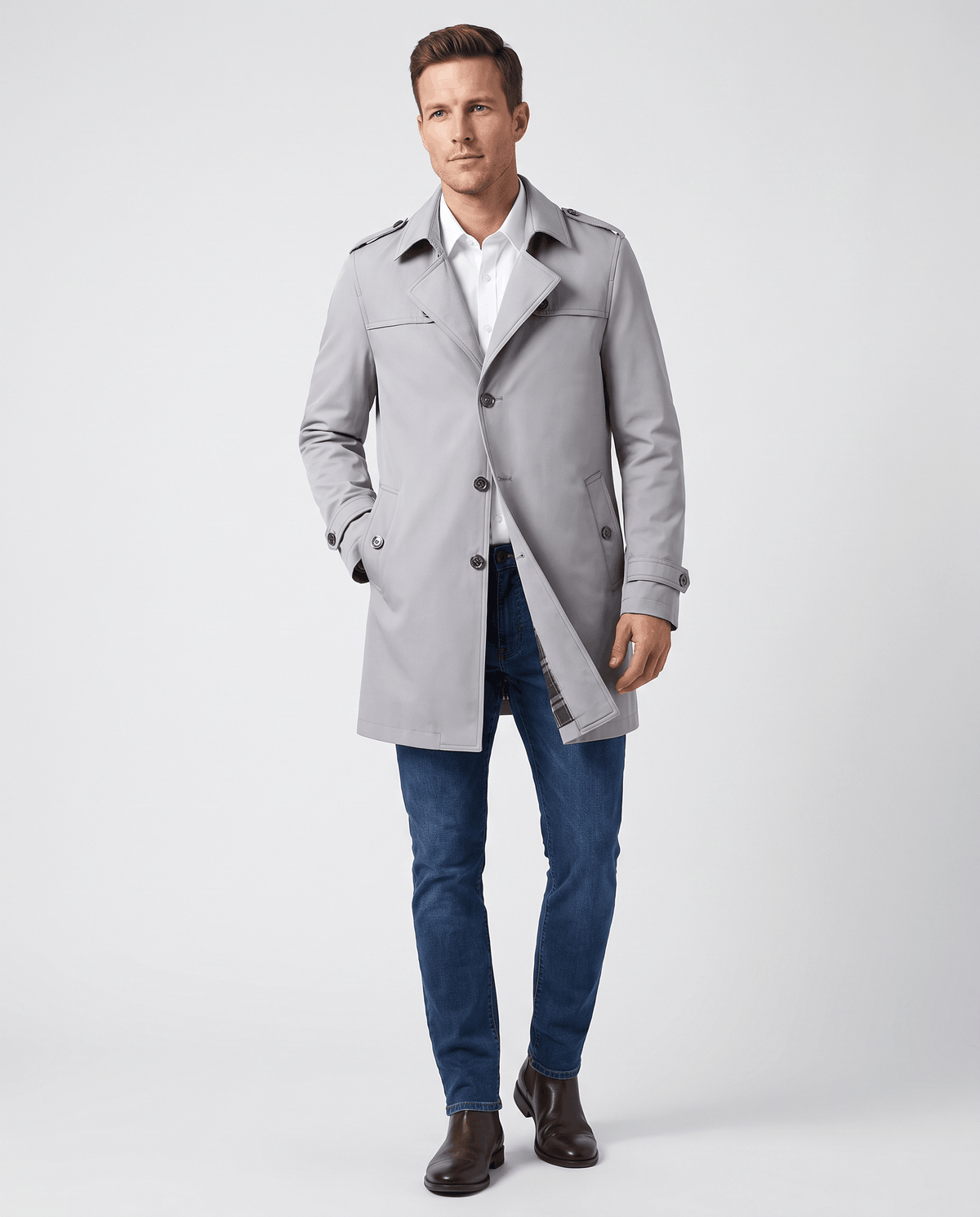 A man wearing a light gray single-breasted trench coat with a mid-length fit, structured lapels, and tailored silhouette