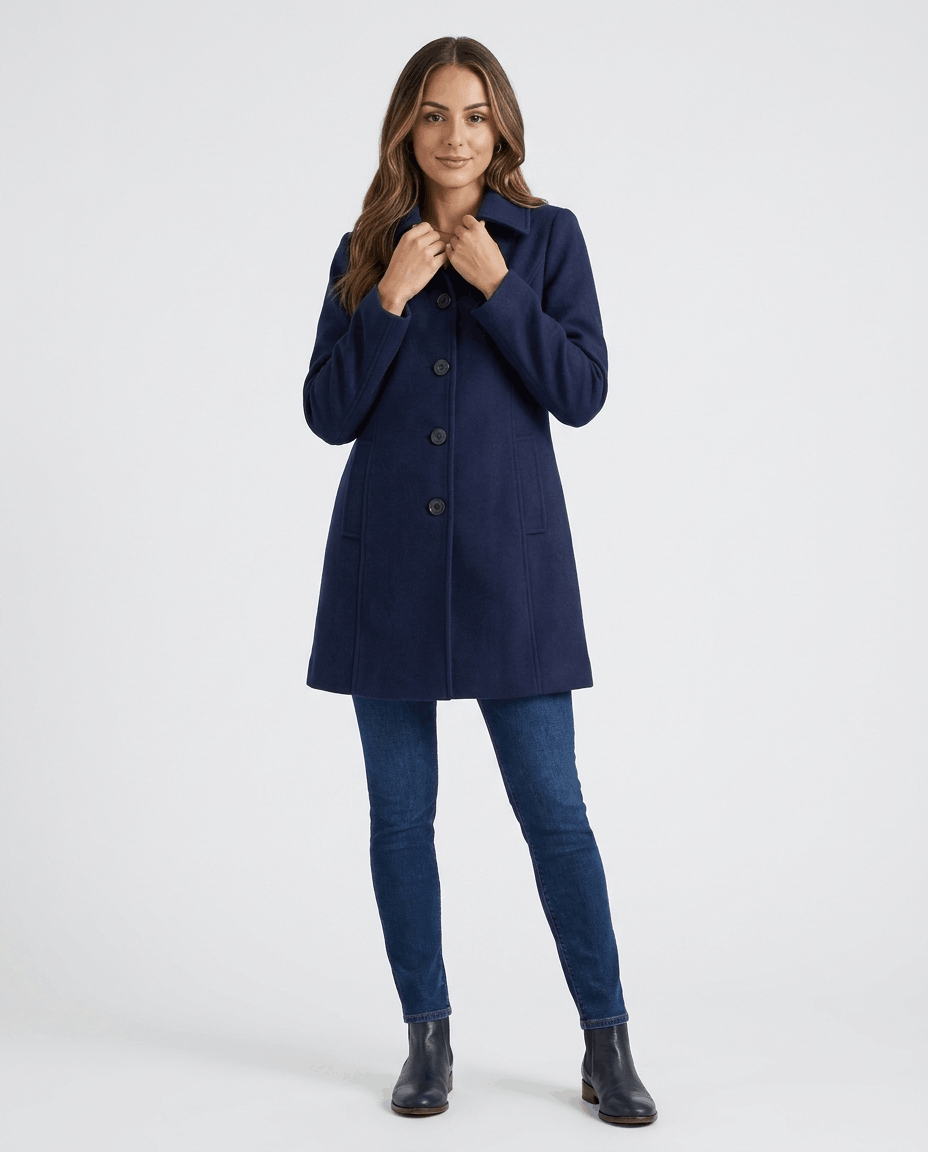 A woman wearing a blue single-breasted mid-length trench coat with a button front and tailored fit