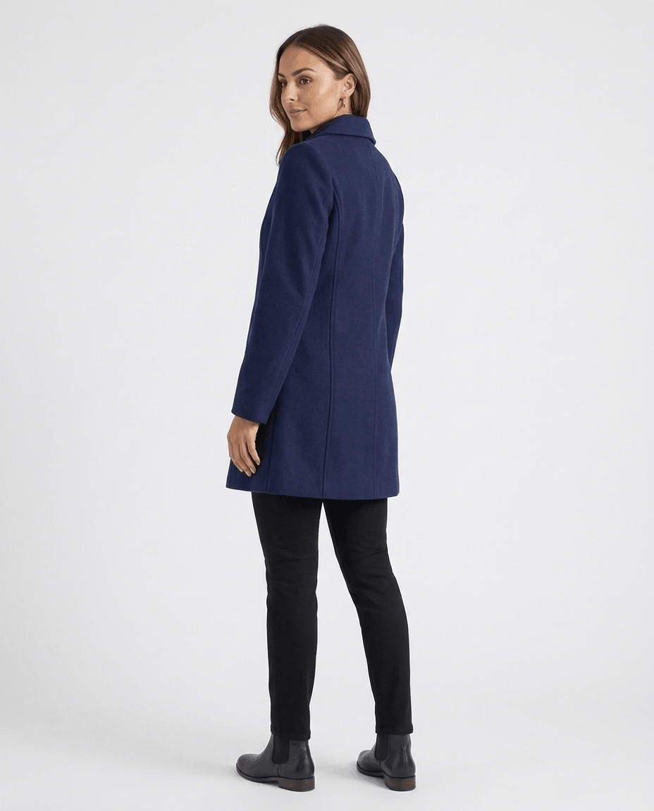 A woman wearing a blue single-breasted mid-length trench coat, shown from the side