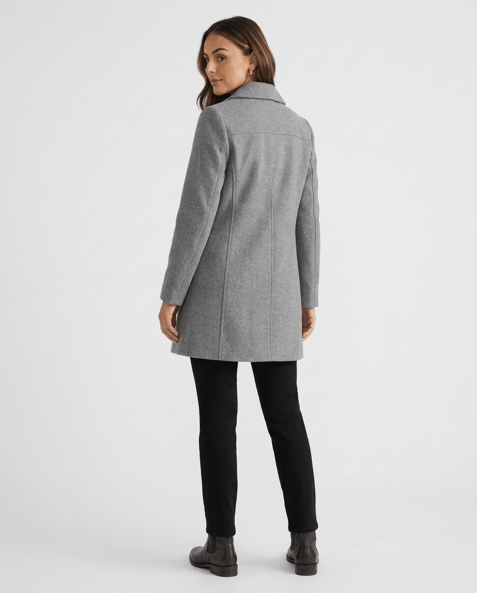 A woman wearing a gray single-breasted mid-length trench coat, shown from the back