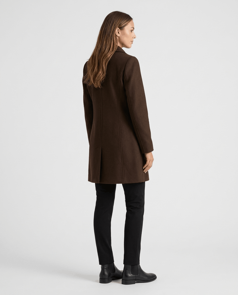 A woman wearing a dark brown single-breasted mid-length trench coat, shown from the back