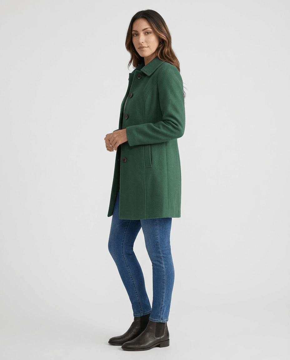 A woman wearing a green single-breasted mid-length trench coat with a button front and tailored fit