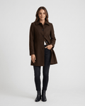 A woman wearing a dark brown single-breasted mid-length trench coat with a tailored fit and button front