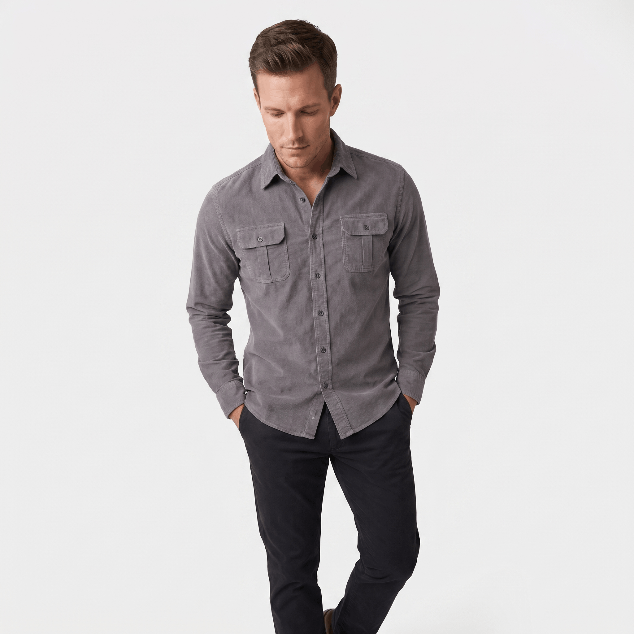 Grey corduroy shirt with a spread collar and twin buttoned flap pockets, worn in a regular fit over dark trousers.