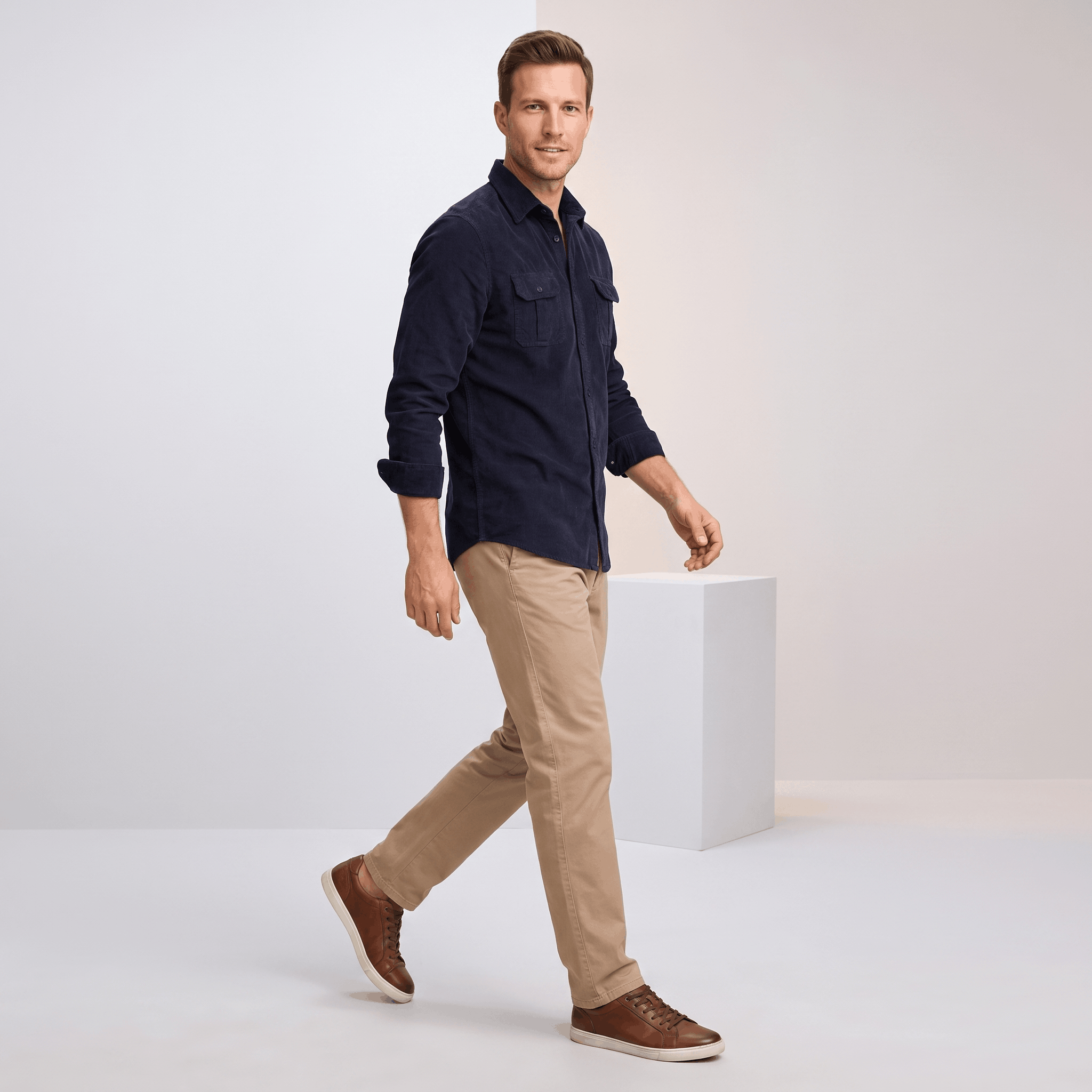 Navy blue corduroy shirt with twin flap pockets and spread collar, worn untucked with tan chinos and brown sneakers.