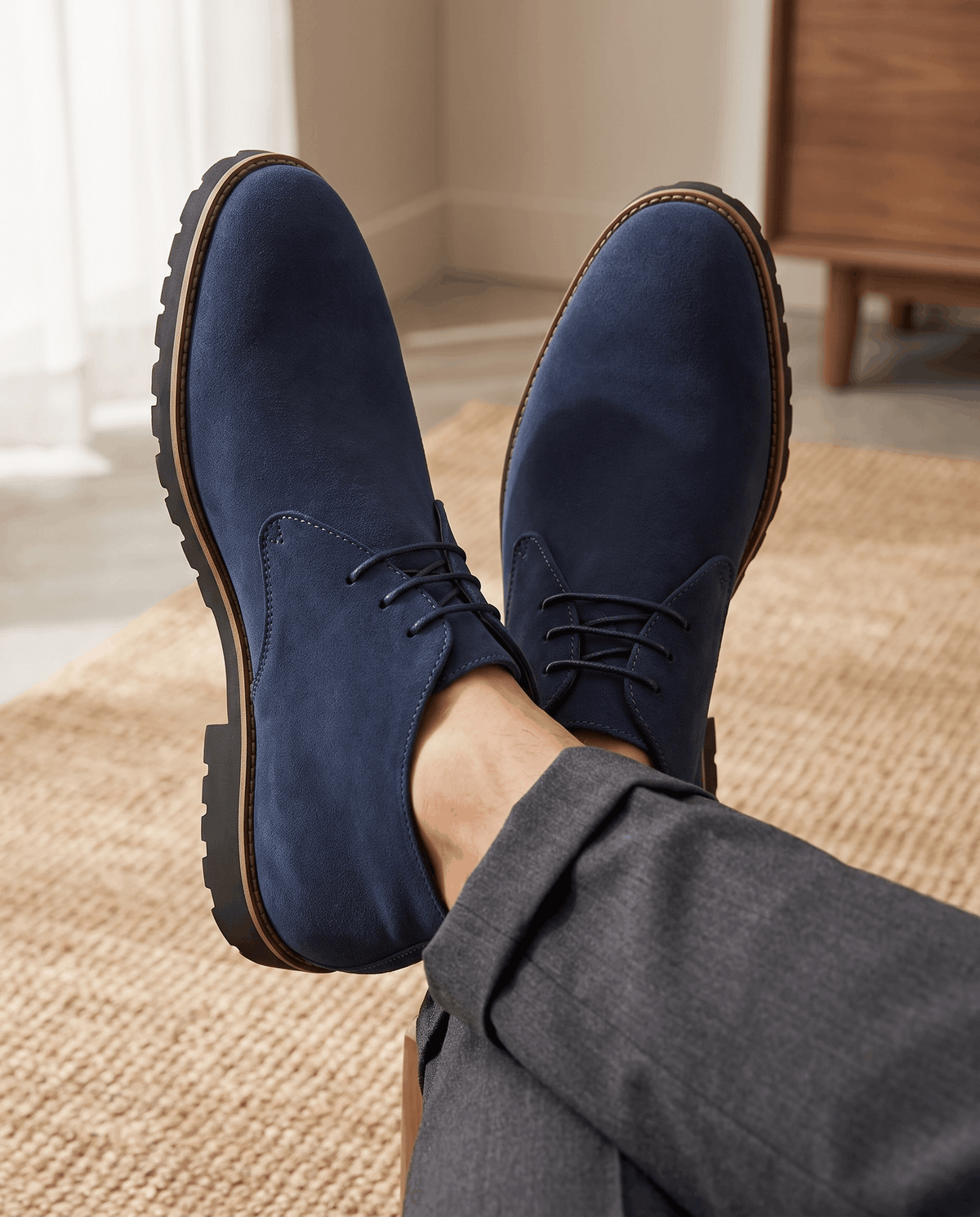 A person wearing navy blue suede ankle boots with lug soles and three-eyelet lacing, shown from above