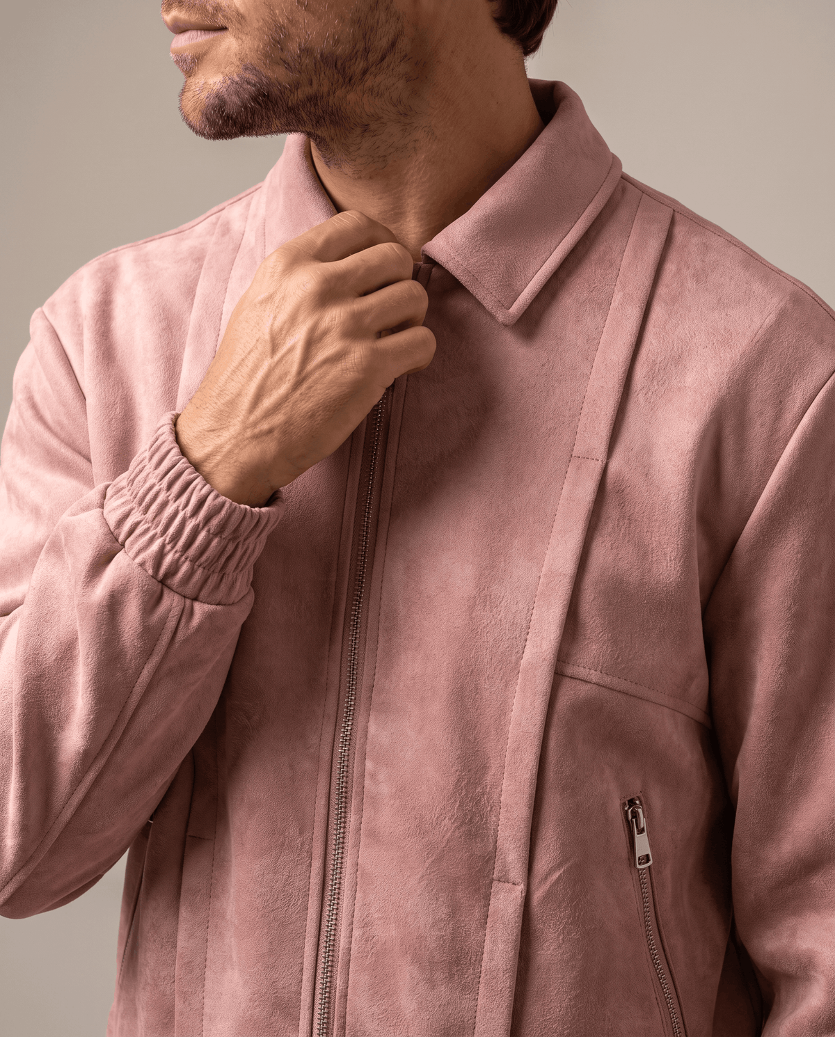 Close-up of a man wearing a pink suede bomber jacket, showing the stand collar and front zip closure