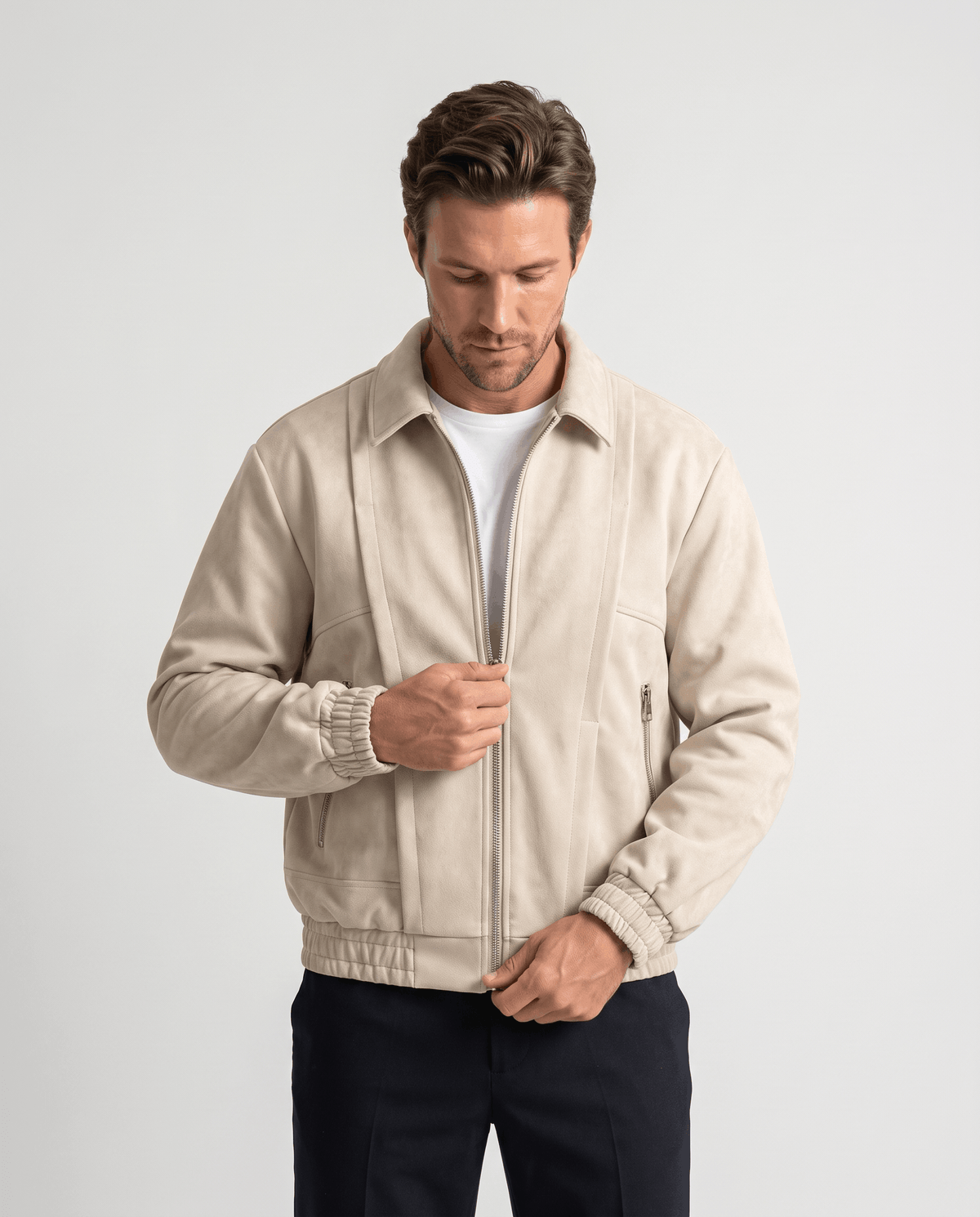 A man wearing a cream suede bomber jacket with a relaxed fit and zip pockets, front view