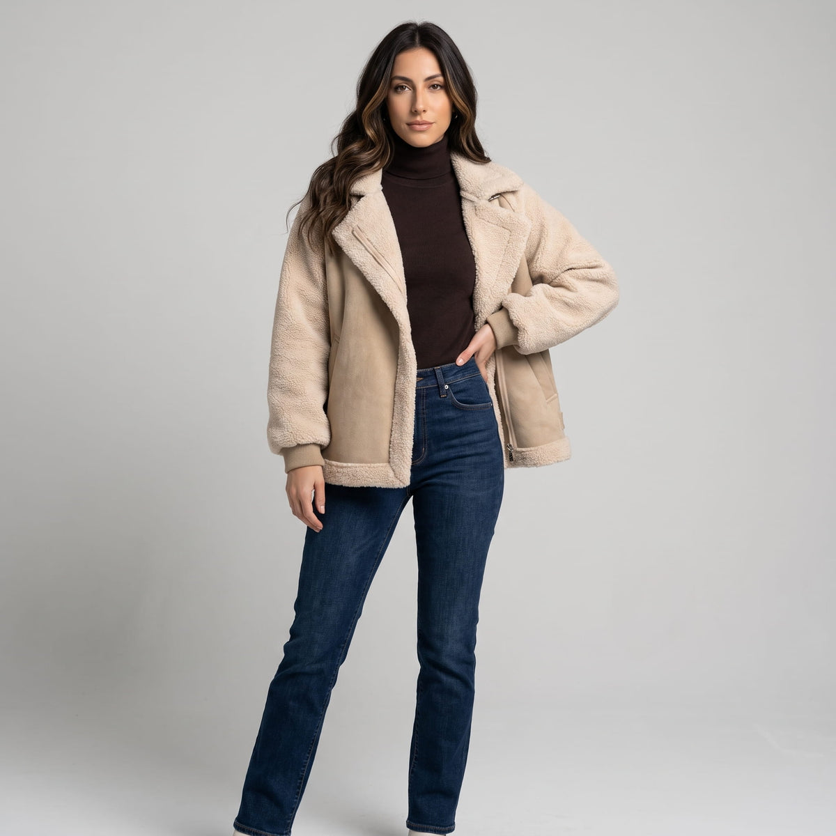 A woman wearing a beige suede leather shearling aviator jacket with an oversized lapel and sherpa trim, front view