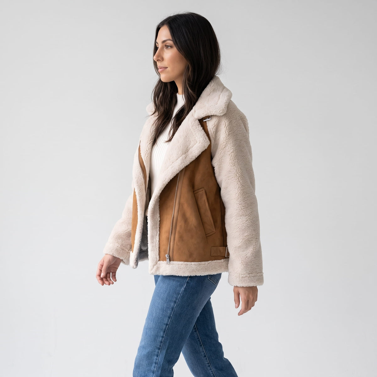 A woman wearing a beige and brown suede leather shearling aviator jacket with an oversized lapel and sherpa trim