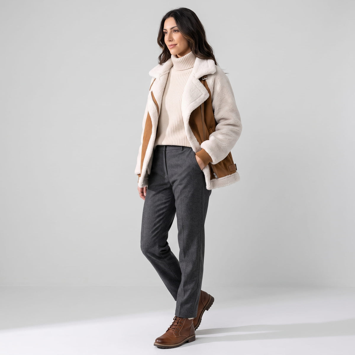 A woman wearing a beige and brown suede leather shearling aviator jacket with sherpa trim, shown from the back