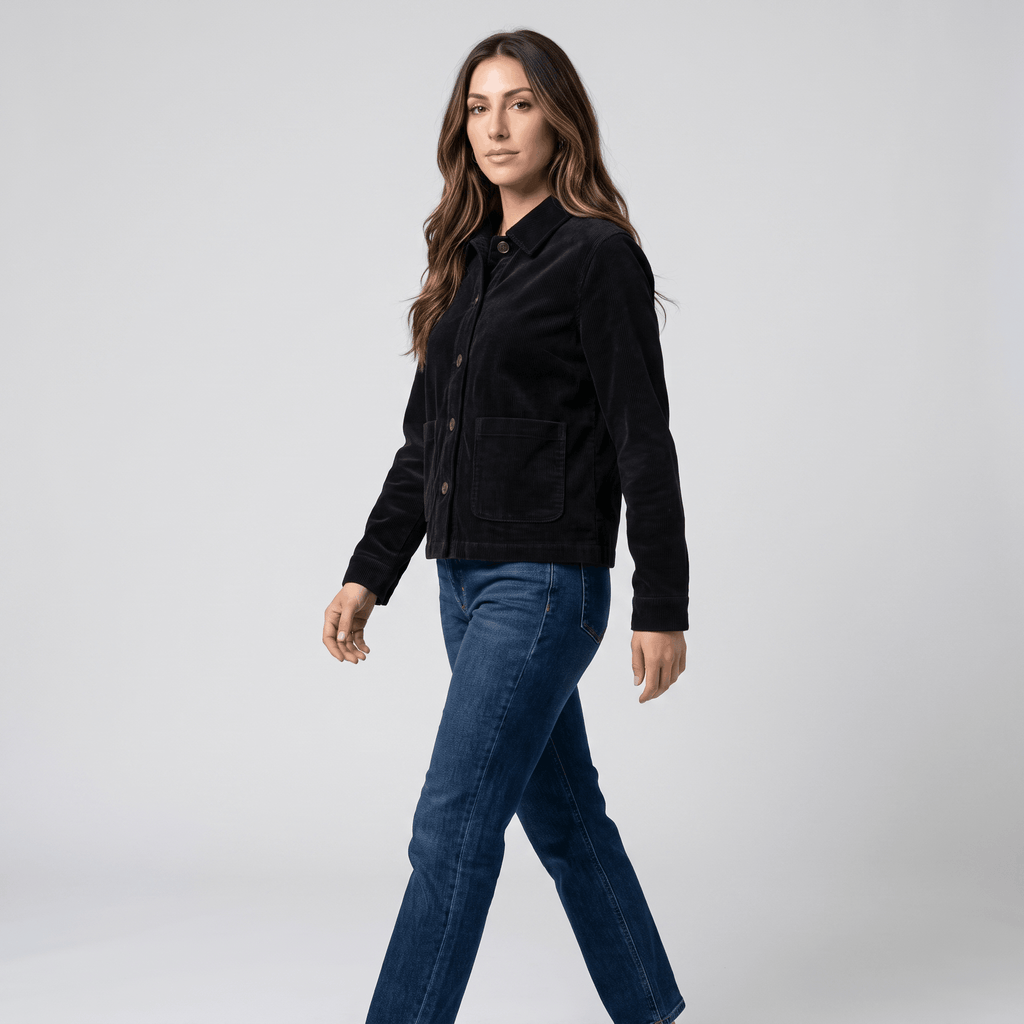 Black cotton corduroy chore jacket with a boxy fit, button-front, and deep patch pockets worn with blue jeans.