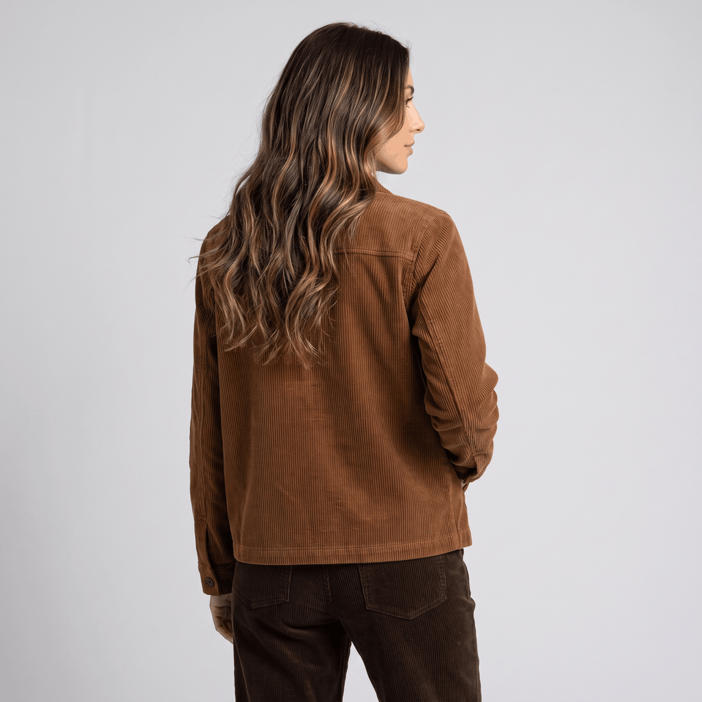 Brown wide-wale cotton corduroy chore jacket with a boxy fit and straight hem, worn over dark corduroy trousers.
