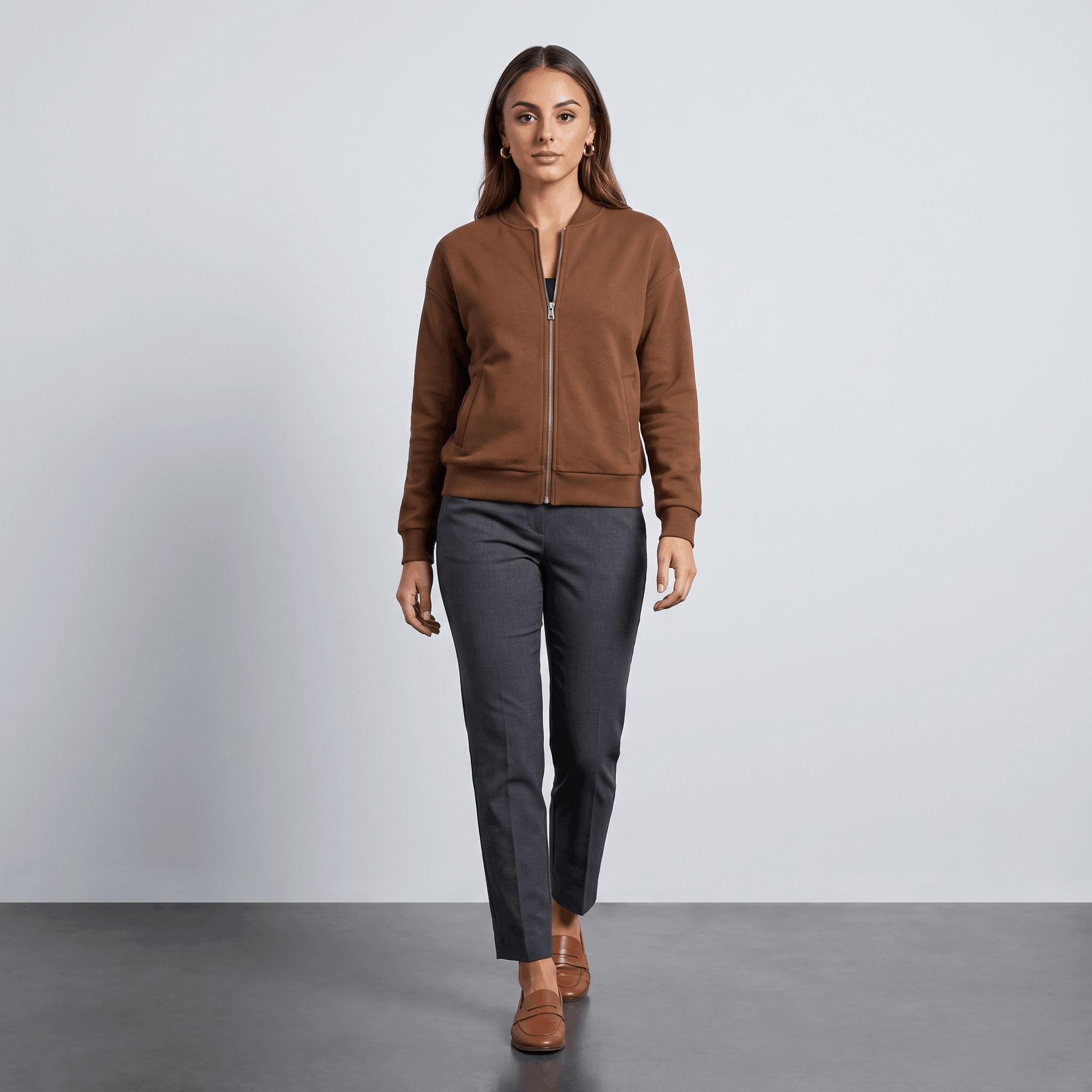Female model wearing the brown zip-up jacket with dark trousers and brown shoes.