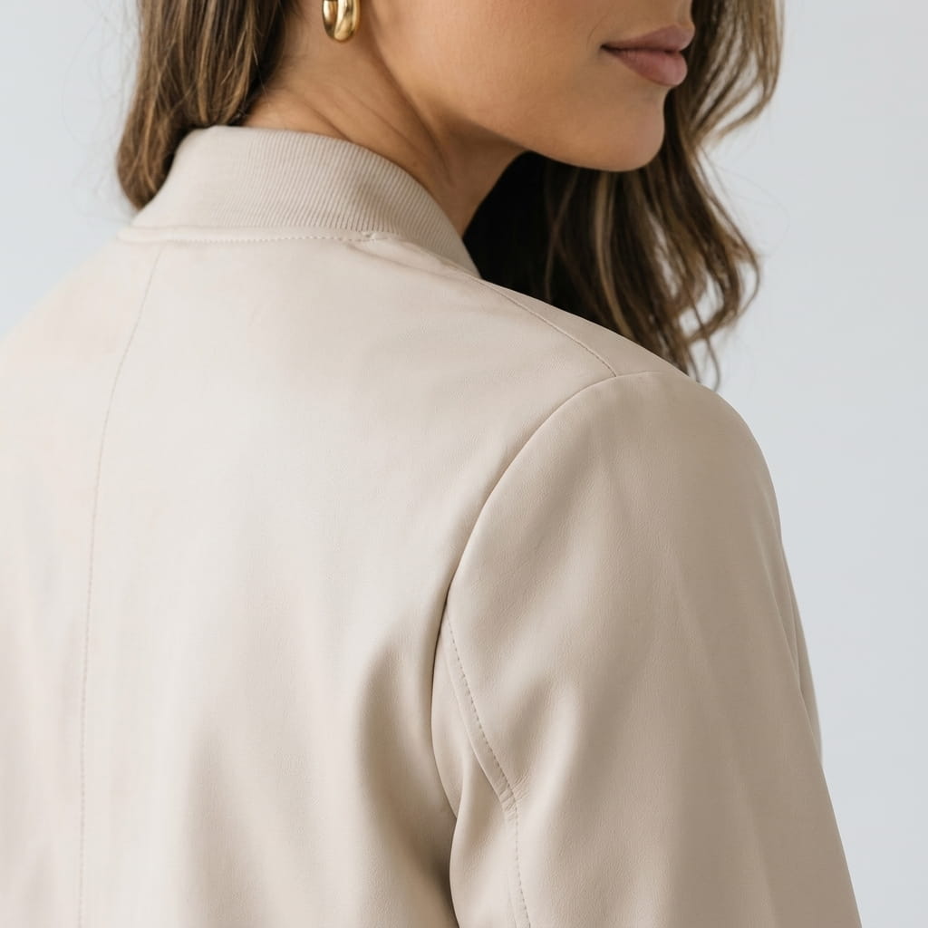 Detailed view of the cream beige jacket, highlighting the stand collar and smooth fabric.