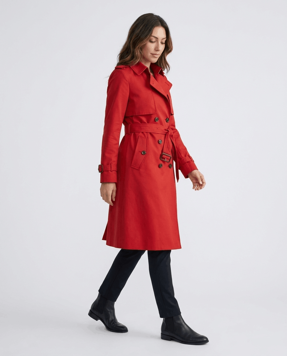 A woman wearing a red mid-length trench coat with a belted waist and button front