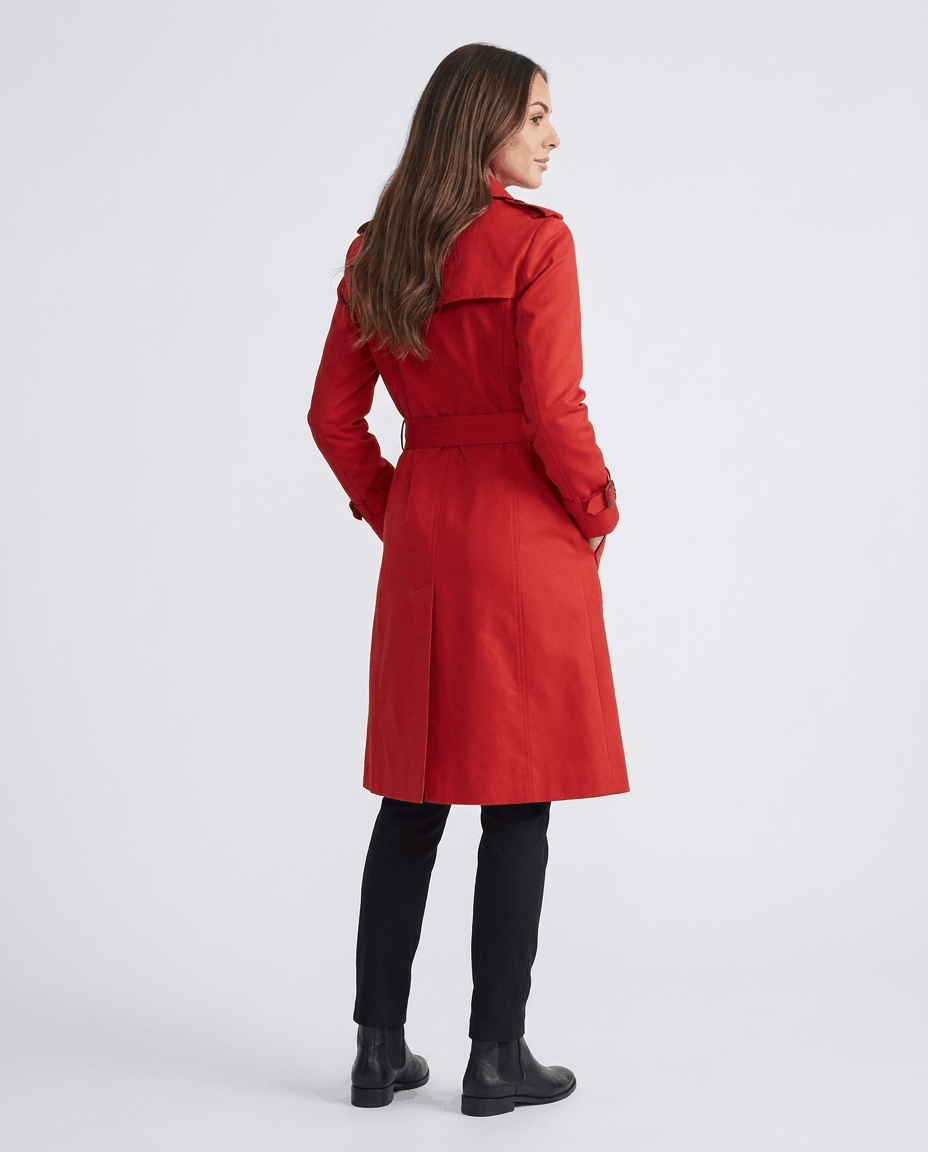 A woman wearing a red mid-length trench coat, shown from the back with a belted waist
