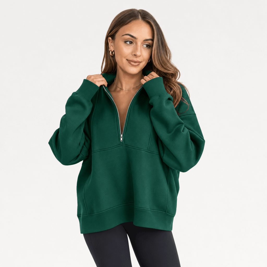 Female model wearing a dark green quarter-zip pullover with black trousers.